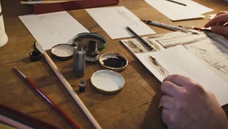 man dipping a pen into ink, camera moving