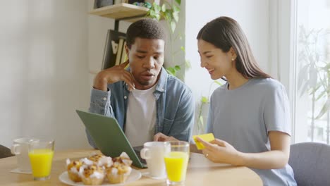 couple having breakfast and using laptop at home