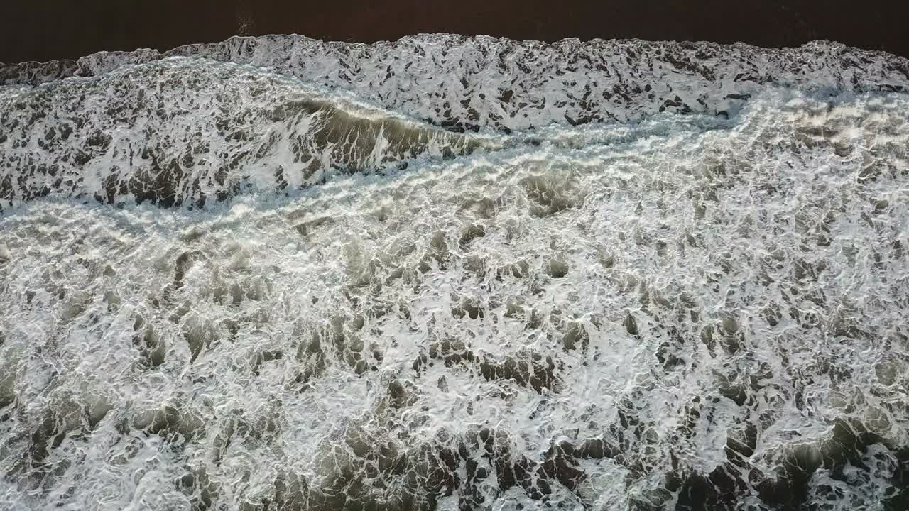 Aerial birds eye view looking down at sea waves crashing down. Green and blue sea top view drone, drone footage