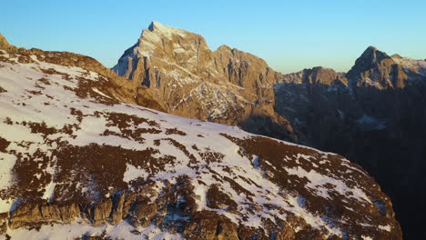 revealing drone shot moving past a rock cliff, mangart mountains in slovenia