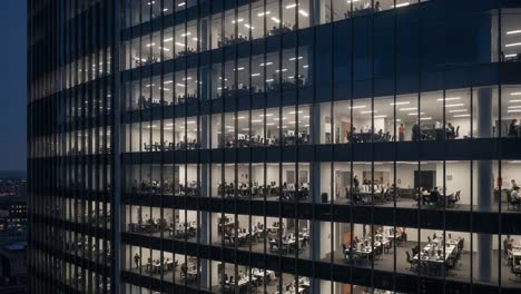 modern office building at night with illuminated workspaces and employees