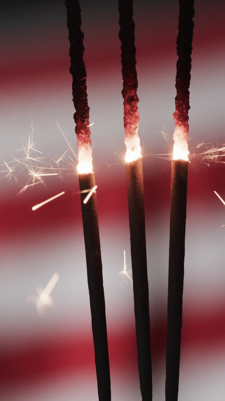 Vertical video of lit sparklers and copy space with flag of usa background