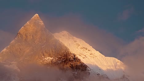 big snowcapped pointy mountain top at sunrise in himalayas mountains in nepal, beautiful dramatic sunrise light and pointed mountain summit close up of massive tall high snowy himalayas peaks in nepal