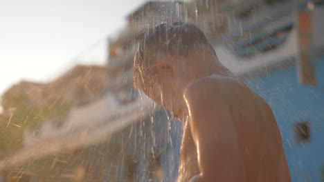 El-Niño-Está-Bajo-Una-Ducha-Fresca-En-La-Playa-Al-Aire-Libre.