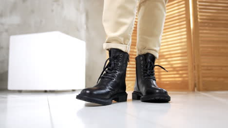 woman's legs in black leather boots and beige pants