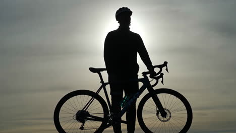 cyclist and bike silhouette against a bright sky