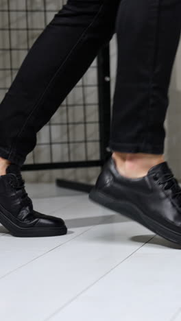 unrecognized man in black jeans and leather sneakers showing moonwalk. stylish male footwear demonstration in studio. vertical video