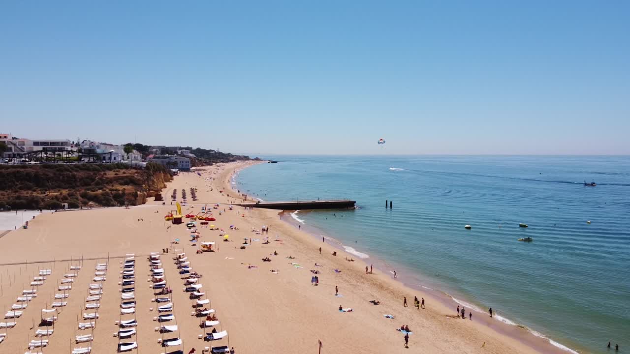 Praia dos Alemães Strand bei Albufeira, Algarve, Portugal – Drohnenansicht des Sandstrandes mit Touristen und Parasailing-Boot
