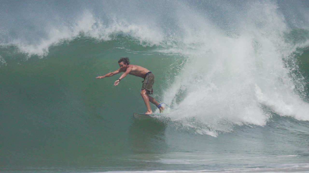 A bare-chested surfer rides deep inside a crystal-clear barrel, showcasing raw surfing skill and tropical wave beauty. Ideal for surf films, ads, and lifestyle content