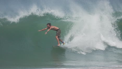 a bare-chested surfer rides deep inside a crystal-clear barrel, showcasing raw surfing skill and tropical wave beauty. ideal for surf films, ads, and lifestyle content