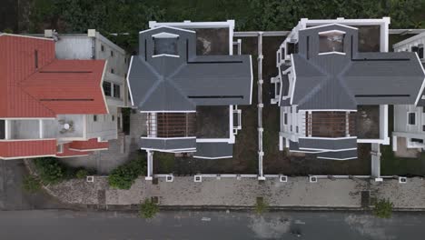 a newly constructed row of identical large white multi story villa styled houses along a suburban road