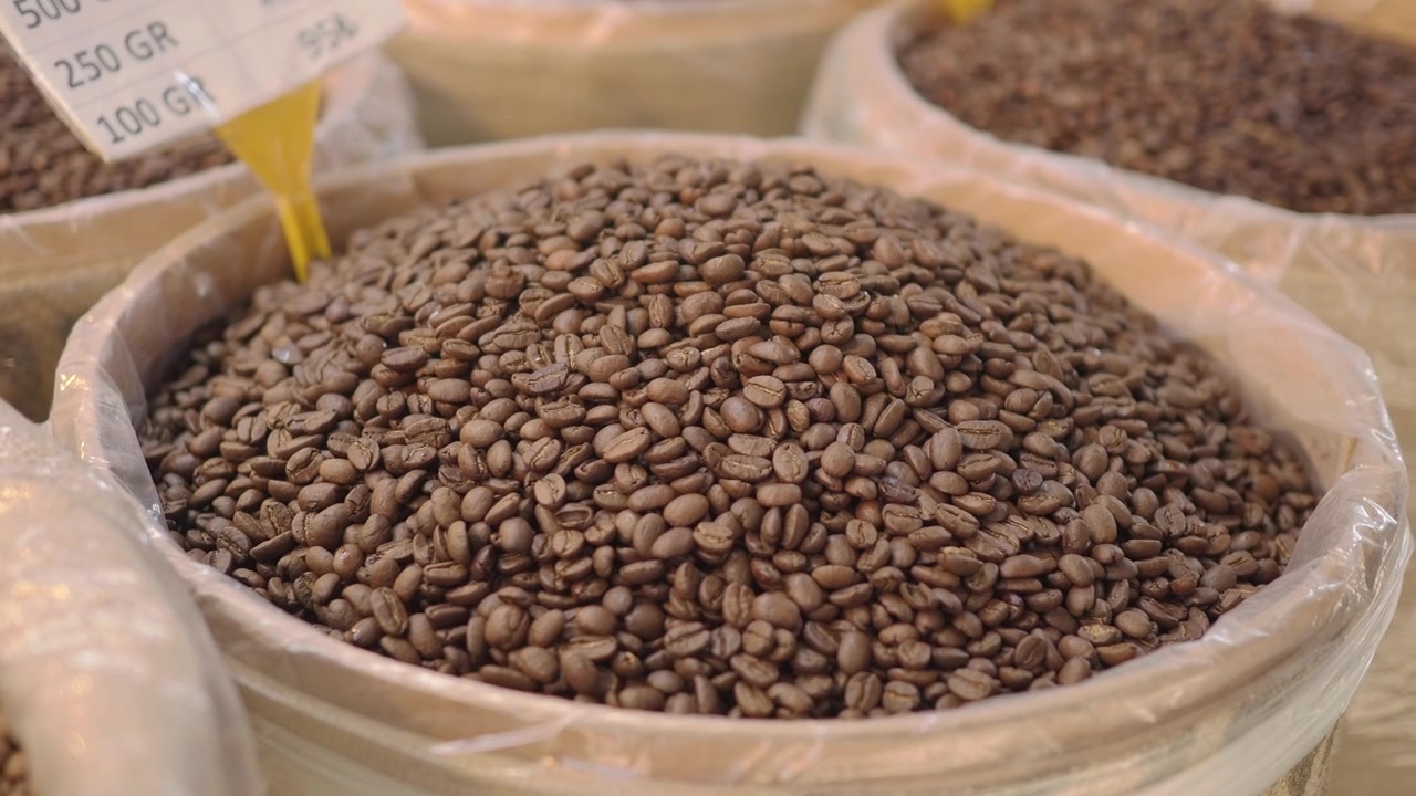 Primo piano di chicchi di caffè crudi in un barile del mercato
