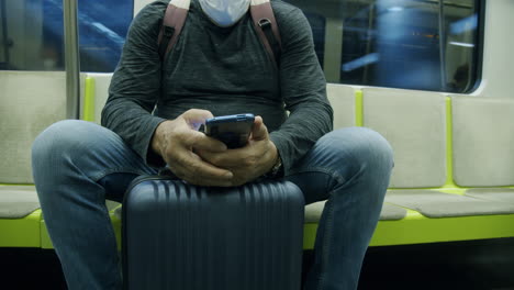 hombre viajero con maleta usando teléfono en el tren del metro