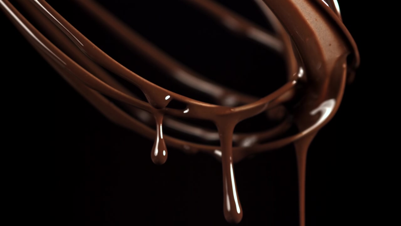 Primo piano di cioccolato fuso che cola dalla frusta al rallentatore