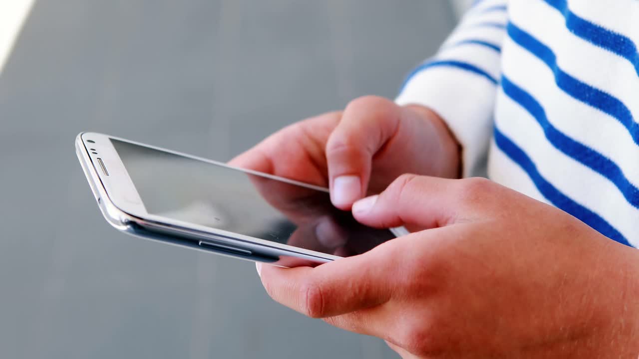 sección media de un niño de escuela usando un teléfono móvil