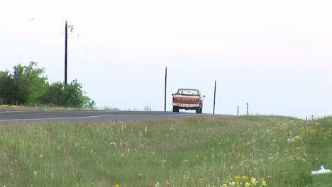 mediumshot of a pickup truck driving down a twolane texas road