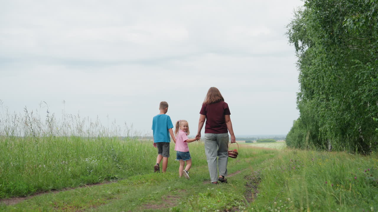 Quiet countryside hike with children and picnic, Peaceful walk through meadow under cloudy sky with family, Serene countryside outing as mother and children enjoy nature and relaxation