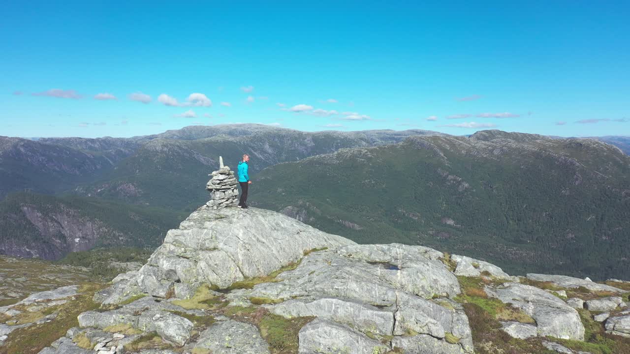 hombre parado en la cima de la montaña y disfrutando del hermoso paisaje montañoso noruego - antena en movimiento hacia adelante que pasa cerca del hombre y continúa hacia el vasto paisaje - stamneshella bolstadfjord
