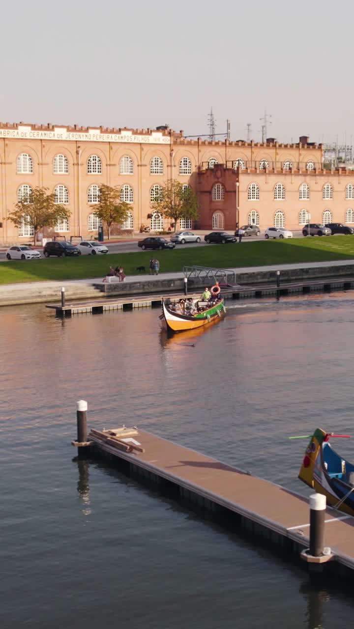 Vista aerea verticale di turisti che si godono una tradizionale crociera in barca moliceiro sui canali della Ria de Aveiro, Portogallo.