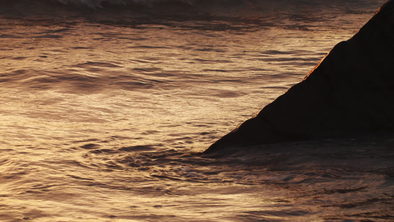 골든 아워 파도가 바위 위에 부히고