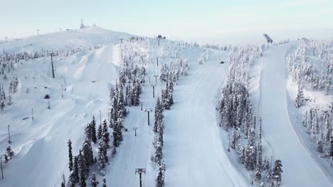Aerial-view-empty-ski-slopes-with-chairlifts-on-snow-covered-mountain