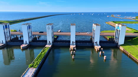 cars move by the bridge over the sluices on the markemeer lake in lelystad, the netherlands. yachts at the blue waterscape at backdrop.