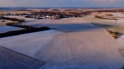 Dusk-Settles-on-a-Snowy-Village-Surrounded-by-Wintery-Fields