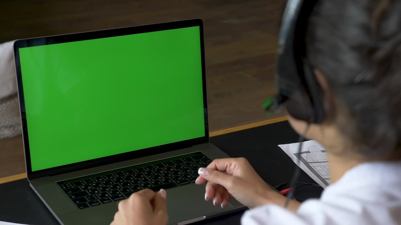 mujer joven en casa sentada en un sofá trabaja en una computadora portátil con pantalla de maqueta verde. niña usando computadora, conferencia telefónica en línea, entrenamiento con personas, usa una computadora. habitación brillante en casa