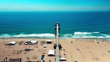 Pier-in-Huntington-Beach-California-high-static-view-of-the-beach,-waves,-surf-and-even-some-people-walking-around