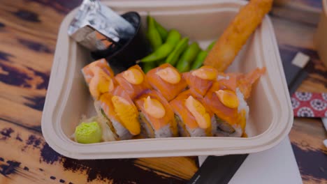 eight piece uramaki sushi in plastic take away box with edamame beans, close up