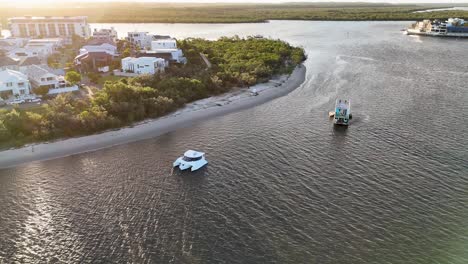 drone footage captures luxury estates and boats along gold coast's serene waterfront during sunset, highlighting lush greenery and calm waters