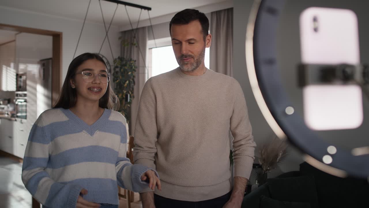 niña adolescente y su padre grabando baile para las redes sociales usando teléfono móvil