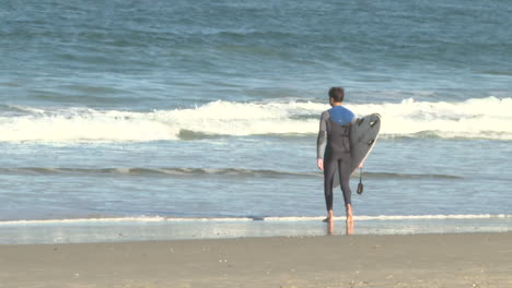 surfer walking into ocean waves at beach