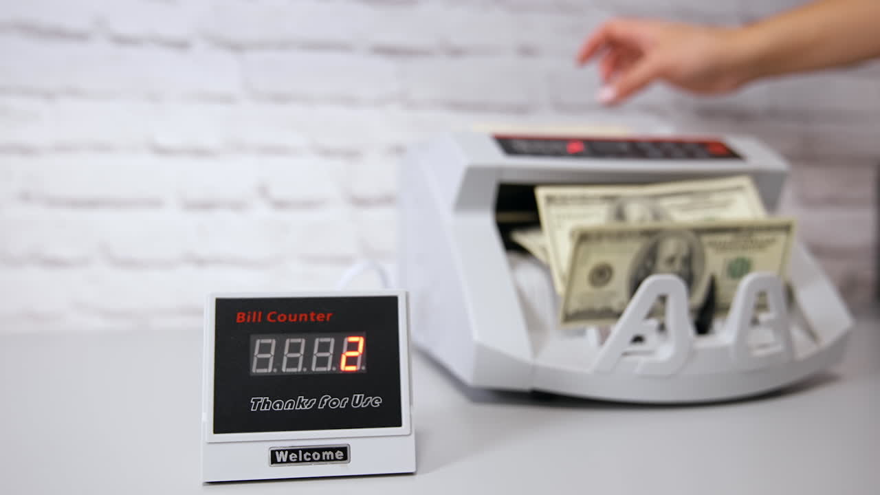 Electronic devices in bank. Bank operations on a counter machine. Automatic mechanism for bank financial operations. Woman puts a bundle of dollars in a money-counting machine with his hand.