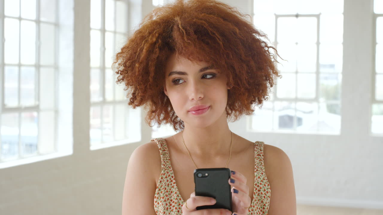 Donna con i capelli afro che messaggia al telefono