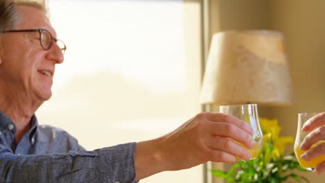 Senior-couple-toasting-glasses-of-juice-at-home-4k