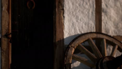 old wood wheel and black door at white house