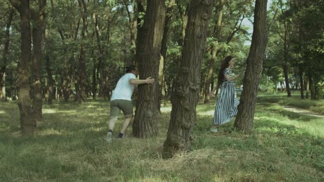 excited pregnant couple playing catch-up in park