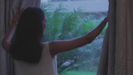 close up shot of woman removing curtain to see rain from window in diu city of india