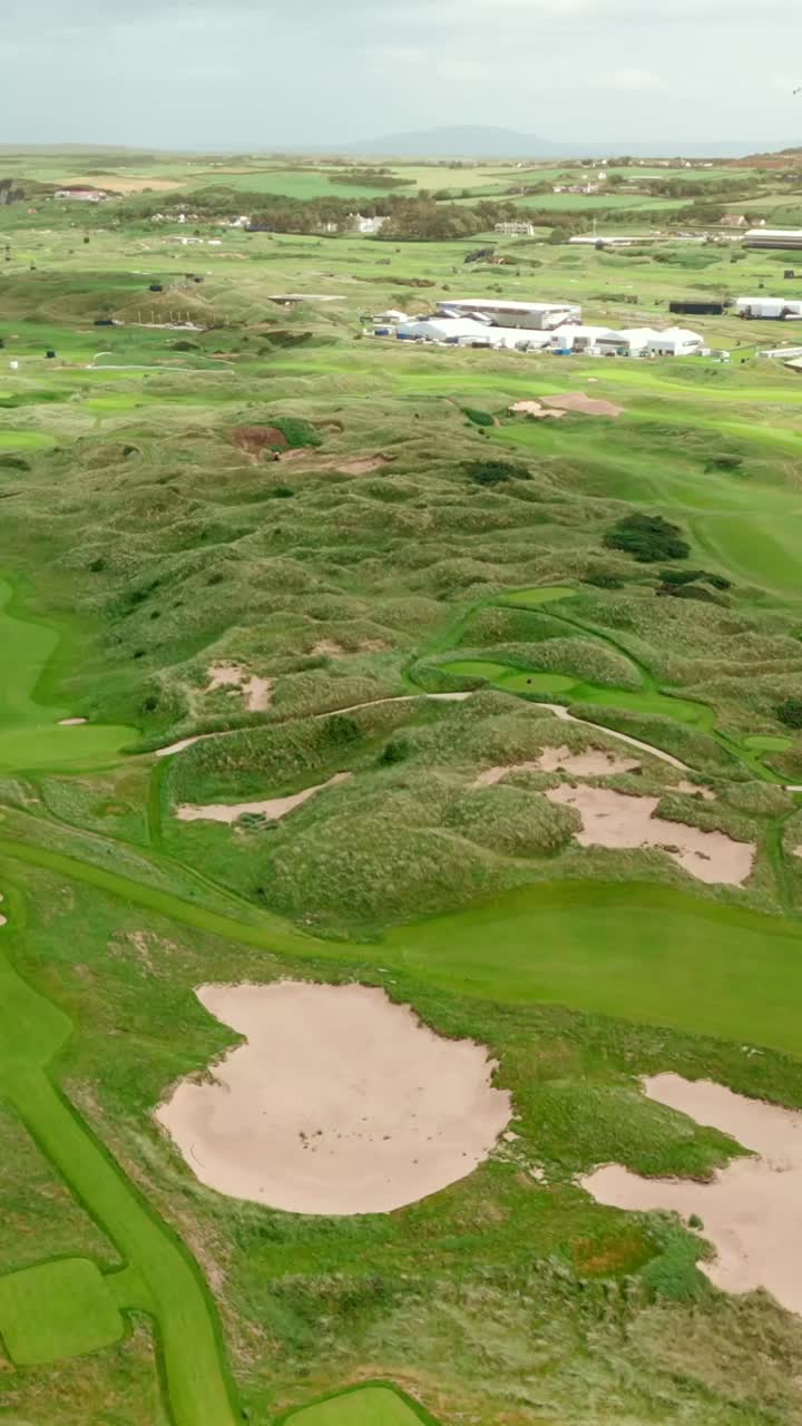Slow reversing social ratio aerial video of Royal Portrush Golf Course in County Antrim, Northern Ireland, UK on a sunny day. Produced in 1080x1920 vertical ratio, 60FPS and with Rec709 color