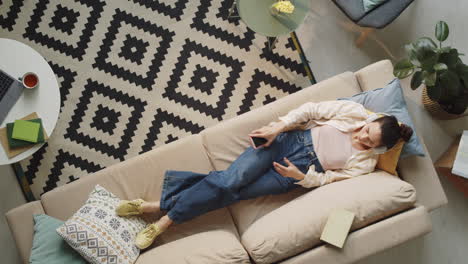 Mujer-Con-Auriculares-Escuchando-Música-En-Un-Smartphone-En-Casa