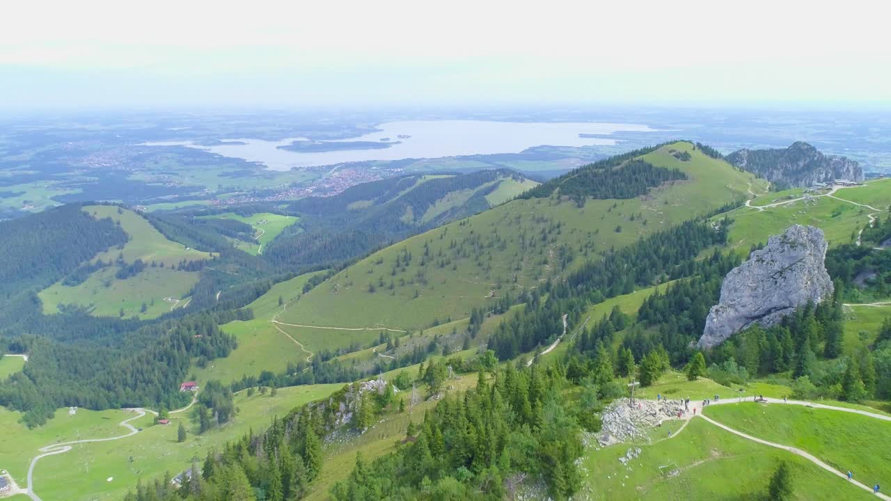 여름에 바이에른 독일의 녹색 산악 스키 슬로프 위로 공중 돌리가 멀리 호수와 계곡을 배경으로 촬영되었습니다.