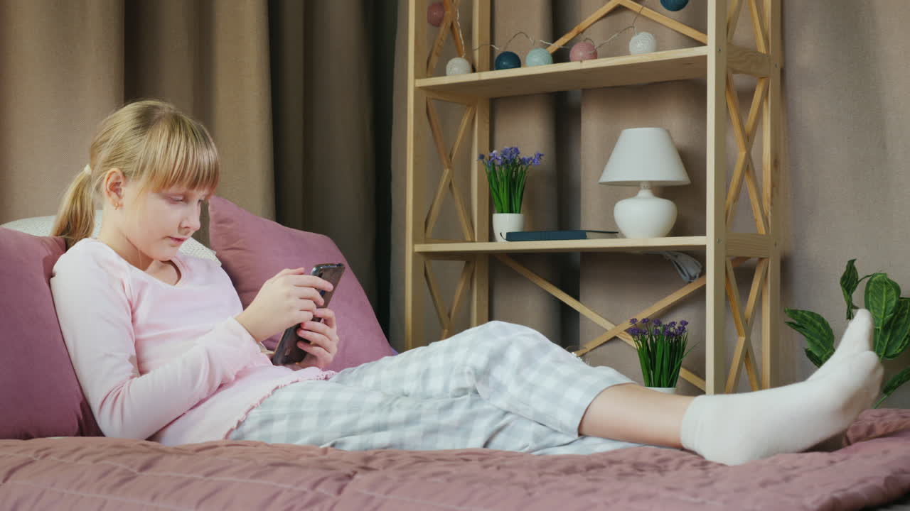 chica rubia en su cama usa un teléfono inteligente