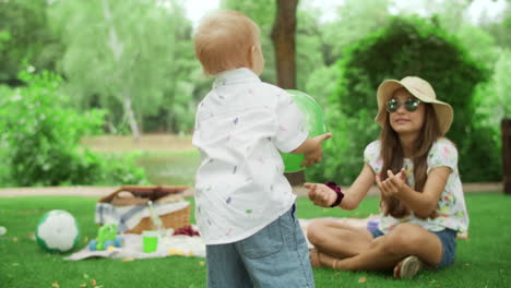 Sister-giving-ball-to-little-brother-in-park.-Children-spending-time-outdoors