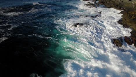 toma aérea de las olas del océano golpeando la costa rocosa chocando violentamente