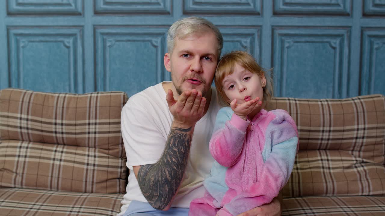 아버지와 딸이 소파에 앉아서 카메라에 미소 짓고 있다