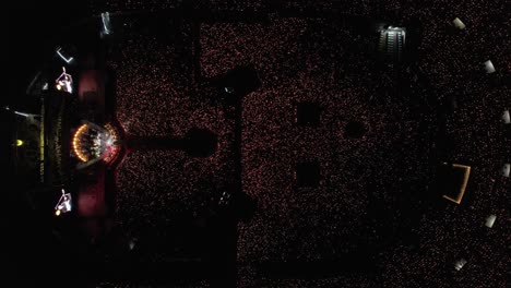 aerial top down view of a concert in a large stadium with a light show emitted by thousands of fans