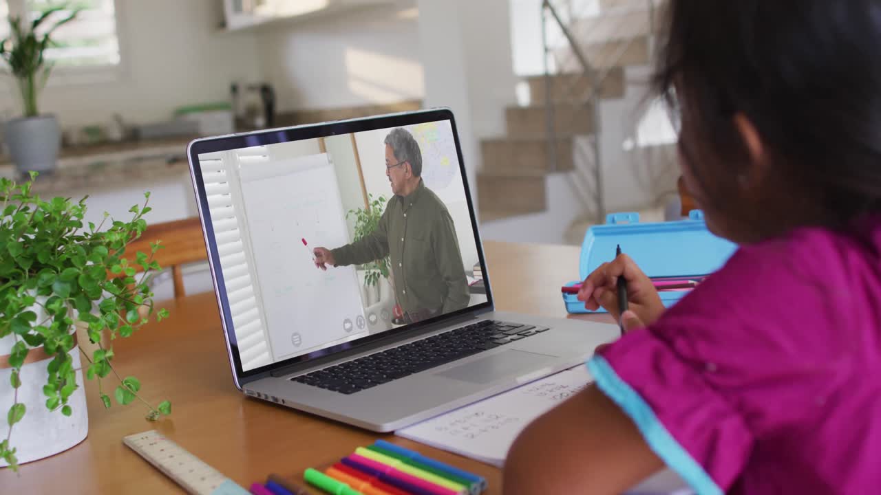 chica afroamericana haciendo la tarea mientras tiene una videollamada con un profesor masculino en una computadora portátil en casa