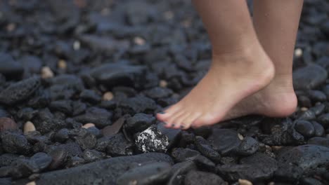 girl-walking-over-black-volcanic-beach-with-small-waves-in-Fuerteventura,-Canary-Islands