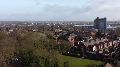 Antena-Que-Establece-Una-Vista-Sobre-Los-árboles-Del-Parque-Hasta-El-Paisaje-Urbano-Industrial-Con-Rascacielos-Azules,-Merseyside,-Inglaterra